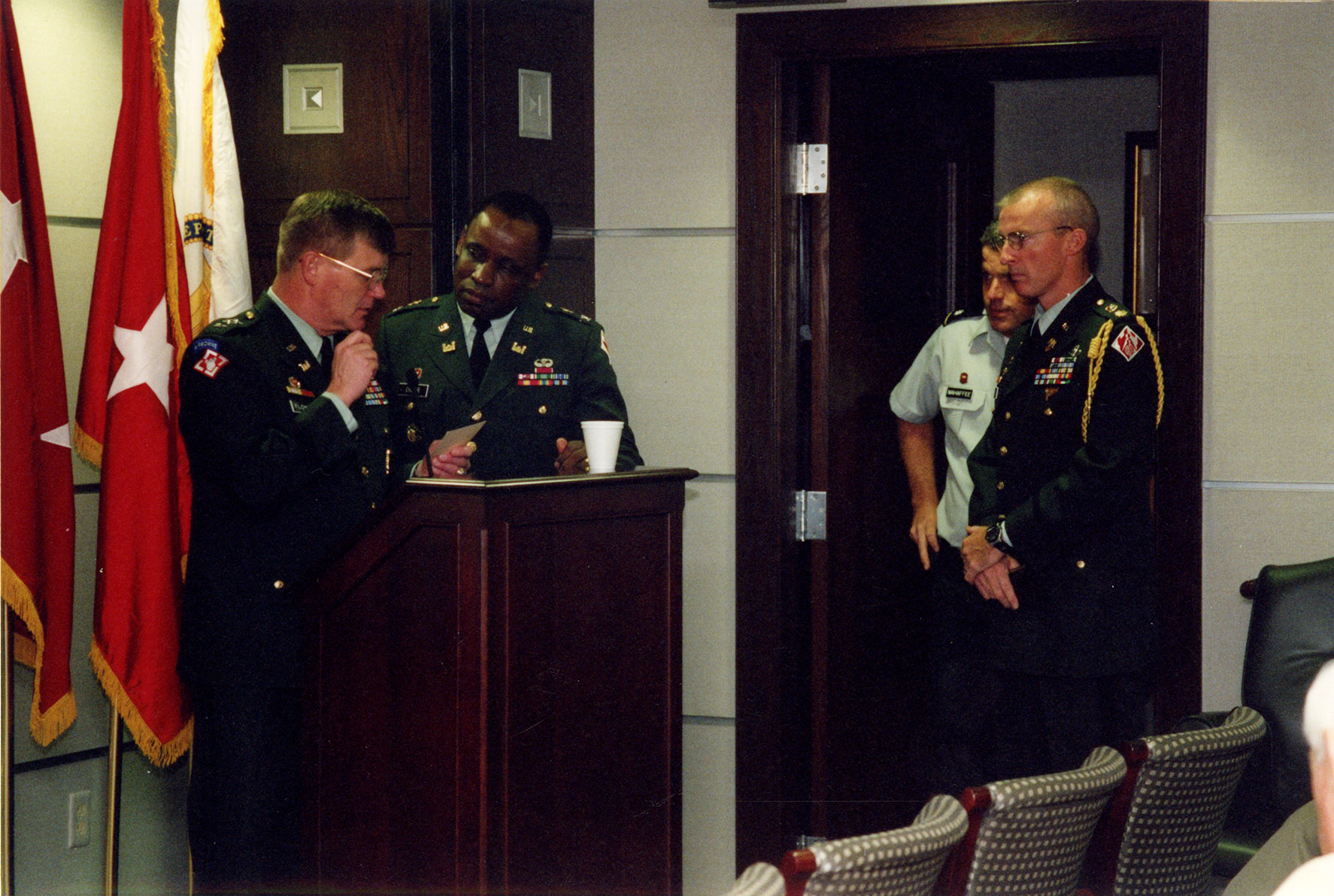 Four men in army uniforms in a meeting room